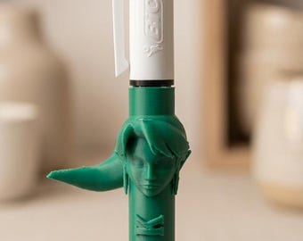 May include: A multi-color BIC ballpoint pen featuring a white top section with a pocket clip and a green 3D-printed barrel. The barrel displays a sculpted character head with pointed ears and the embossed text LINK, standing on a small cork base.