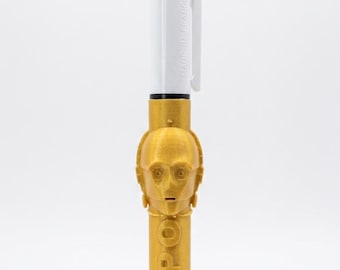 May include: A multi-color retractable ballpoint pen featuring a white top section with green, blue, and red ink selectors and a gold-colored lower barrel molded with the head of a robotic character and the embossed text C3PO on the side.