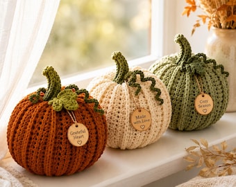 Può includere: Tre zucche all'uncinetto nei colori arancione, crema e verde salvia. Ogni zucca presenta un gambo verde, un viticcio riccio e un'etichetta rotonda in legno. Le etichette riportano le scritte Grateful Heart, Made with Love e Cozy Season.