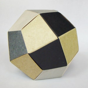 Pode incluir: Uma escultura de papel geométrica com um esquema de cores preto, prata e marrom. A escultura é feita de papel dobrado e tem um design único e abstrato.