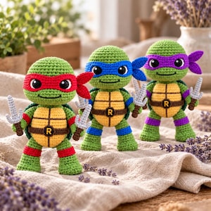 Peut inclure: Trois poupées tortues au crochet avec des corps verts et des carapaces beiges. Chacune porte un masque coloré rouge, bleu ou violet, et une ceinture marron avec une boucle R. Elles tiennent de petites armes grises au crochet sur un tissu.