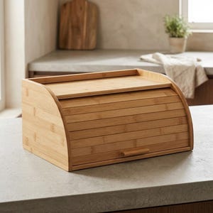 May include: A rectangular bamboo bread box featuring a roll-top lid with horizontal slats and a small wooden handle. The container has a light brown natural wood grain finish and a flat top surface, designed for storing baked goods.