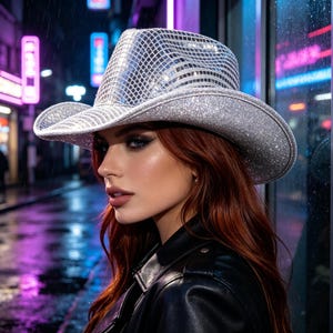 Op de afbeelding: Een zilveren cowboyhoed met een reflecterend, ruitvormig oppervlak en een glitterende textuur. De hoed heeft een brede, gebogen rand en een gestructureerde kroon, afgewerkt met een metallic glans die het licht op opvallende wijze weerkaatst.