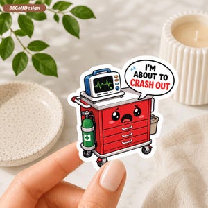 May include: A die-cut sticker featuring a red medical crash cart with a cartoon face showing a distressed expression. The cart holds a heart monitor and a green oxygen tank. A speech bubble above reads, I'M ABOUT TO CRASH OUT in black and red text.