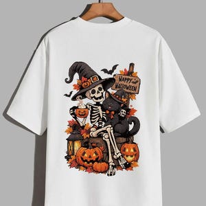 May include: A white short-sleeve t-shirt featuring a graphic print of a skeleton wearing a witch hat, sitting with a black cat. The design includes pumpkins, autumn leaves, a lantern, and a wooden sign that reads Happy Halloween.