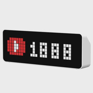 May include: A rectangular digital display device with a white casing and a black screen. The screen features a red pixelated circular icon with a white play symbol, followed by the white pixelated numerical sequence 1888 on a black background.