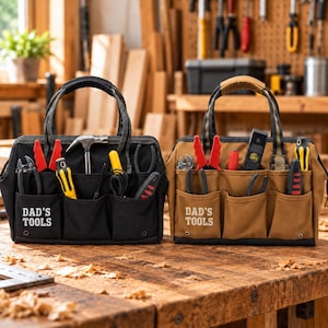 May include: Two canvas tool bags, one black and one tan, each featuring the text DAD'S TOOLS printed in white. Both bags have multiple exterior pockets filled with various hand tools, including pliers, screwdrivers, a hammer, and a level.