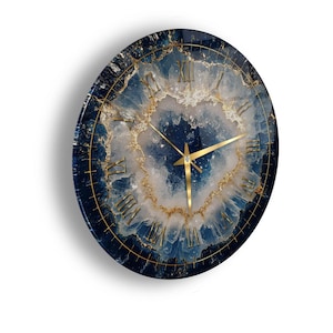 May include: A circular wall clock featuring a deep blue and white geode-inspired pattern with gold-coloured accents. The clock face displays gold Roman numerals and thin gold hands, set against a dark, marbled background with crystalline textures.