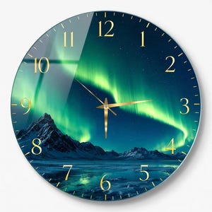 Pode incluir: Um relógio de parede redondo com uma vibrante aurora boreal verde sobre uma paisagem montanhosa azul-escura. O mostrador inclui numerais dourados e ponteiros finos de cor dourada, sobre uma superfície brilhante com um céu estrelado.