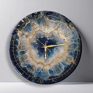 May include: A round wall clock featuring a deep blue and white geode-inspired pattern with gold-colored accents. The clock face displays gold Roman numerals and thin gold hands, creating a layered, crystalline appearance across the circular surface.