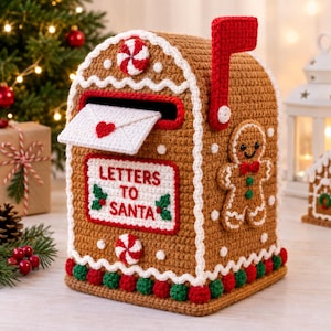 Op de afbeelding: Een bruine gehaakte brievenbus in de vorm van een peperkoekhuisje met witte glazuurranden, een rode vlag en een witte envelop met een rood hartje. De voorzijde bevat de rode tekst "LETTERS TO SANTA" en is versierd met een peperkoekmannetje.