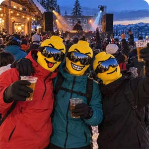 Könnte beinhalten: Drei Personen tragen leuchtend gelbe, geformte Kopfbedeckungen, die an Spielfiguren erinnern, kombiniert mit dunklen Skibrillen. Sie tragen Winterjacken und schwarze Handschuhe und halten jeweils einen durchsichtigen Plastikbecher mit Getränk.