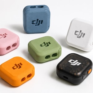 Puede incluir: Seis unidades transmisoras DJI cuadradas en varios colores, incluyendo rosa, azul, blanco, verde oliva, naranja y un modelo negro translúcido. Cada dispositivo presenta el logotipo de DJI en relieve en la parte superior y dos puertos circulares.
