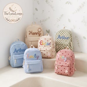 Puede incluir: Una colección de seis mochilas de pana en varios colores, incluyendo azul claro, beige y rosa, con patrones de lunares y cuadros. Cada mochila está personalizada con nombres bordados como Henry, Arthur, Eloise, Emily y Freya.