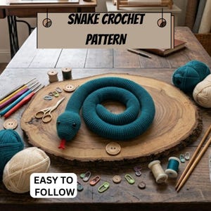 Peut inclure: Un serpent crocheté bleu sarcelle avec des yeux noirs et une langue rouge, accompagné de pelotes de laine, crochets, ciseaux, boutons et marqueurs de mailles. L'image affiche le texte SNAKE CROCHET PATTERN et EASY TO FOLLOW sur une surface en bois.