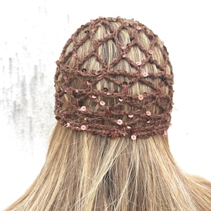 Op de afbeelding: Een bruin gehaakt haaraccessoire met een ruitvormig netpatroon, versierd met kleine, reflecterende bruine lovertjes door de hele garenstructuur. Het accessoire is ontworpen om nauwsluitend over de bovenkant van het hoofd te passen.