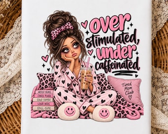May include: A white rectangular item featuring a graphic of a person with brown hair in a messy bun, wearing pink heart-patterned pajamas and smiley face slippers. The text reads "OVER STIMULATED, UNDER CAFFEINATED", "Tired Mom Club", and book titles.