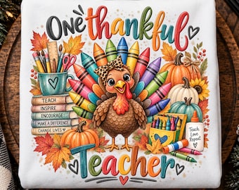 May include: A white sweatshirt featuring a colorful graphic of a turkey with crayon feathers, a stack of books labeled Teach, Inspire, Encourage, Make a Difference, Change Lives, pumpkins, and the text One thankful Teacher with a glue bottle.