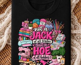 May include: A black t-shirt featuring a colorful graphic print of various craft supplies including yarn, a sewing machine, a cutting machine, markers, and a potted plant, with the text "not a JACK of all trades but a HOE of all hobbies".
