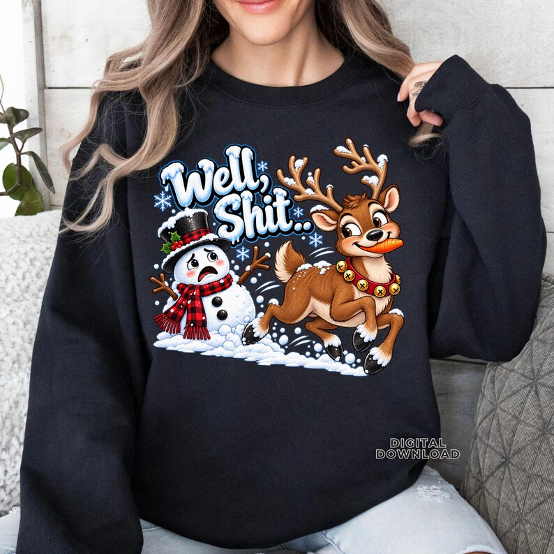 May include: A black long-sleeve sweatshirt featuring a graphic of a startled snowman wearing a red and black plaid scarf and a top hat, alongside a reindeer with a carrot in its mouth, with the text "Well, Shit.." in blue and white letters.