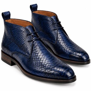 May include: A pair of ankle boots featuring a deep blue snakeskin-textured finish, a lace-up front with matching blue laces, a pull tab at the heel, a tan interior lining, and a dark brown stacked heel with a black rubber outsole.