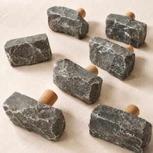 May include: A set of six cabinet knobs, each featuring a rough, dark gray, rectangular stone face with a natural textured surface and a smooth, cylindrical light brown wooden base attached to the back for mounting purposes.
