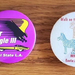 May include: Four round buttons with text and graphics. One orange button says "Make it Happen" in white. A purple button has "Solar Eagle III" and a graphic. A white button says "Walk on the Wild Side!" with animal graphics. Another white button says "Guest" with a giraffe.