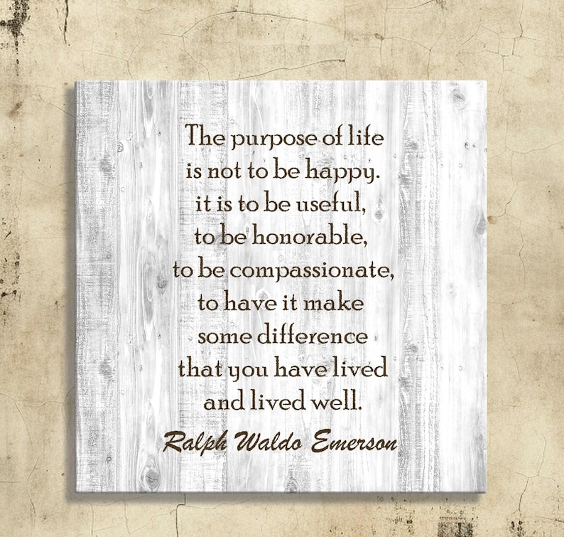 Peut inclure: Panneau carr&eacute; en bois avec un fond blanc effet grain de bois. Le panneau affiche une citation de Ralph Waldo Emerson en texte marron : "Le but de la vie n'est pas d'&ecirc;tre heureux..." Le panneau est mont&eacute; sur un mur beige.