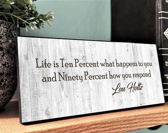 May include: A white wooden sign with a black border and the quote "Life is Ten Percent what happens to you and Ninety Percent how you respond - Lou Holtz" in black text.