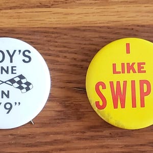 May include: Four vintage pinback buttons. One white button has text and a design that says "1979 CSSA Ceremonial Session Denver, Colorado". Another white button says "Indy's Fine in '79". A yellow button says "I Like Swipe". The last button has a hot air balloon and says "I Visited Pikes Peak Country Colorado".