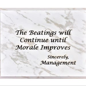 May include: A rectangular plaque with a marble-like pattern and a white border. The text reads "The Beatings will Continue until Morale Improves Sincerely, Management" in black font.