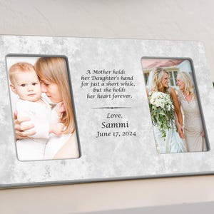May include: A white marble picture frame with two openings for photos. The frame has a quote about a mother's love for her daughter: "A Mother holds her Daughter's hand for just a short while, but she holds her heart forever." The quote is followed by "Love, Sammi June 17, 2024".