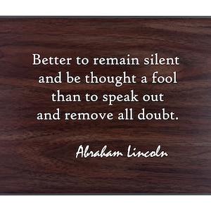 May include: A dark brown wooden plaque with a white quote by Abraham Lincoln: "Better to remain silent and be thought a fool than to speak out and remove all doubt."