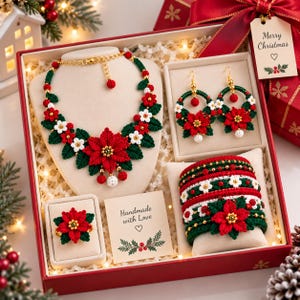 May include: A jewellery set featuring a crocheted necklace, hoop earrings, a ring, and a bracelet, all decorated with red poinsettia flowers, white blossoms, and green leaves. The set is presented in a gift box with a card reading Handmade with Love.