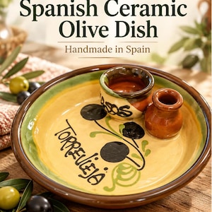 Può includere: Un piatto rotondo in ceramica spagnola per olive con base gialla, bordo verde e finitura marrone. Il piatto include una piccola tazza integrata e un vasetto separato, decorato con illustrazioni di olive nere e la scritta Torrevieja.