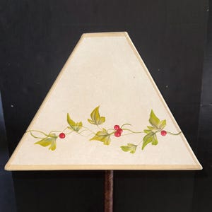 Op de afbeelding: Een driehoekige lampenkap met een crèmekleurige achtergrond en een geschilderd ontwerp van groene bladeren en rode bessen.