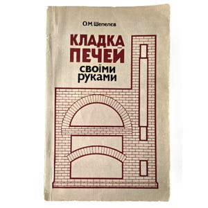 Puede incluir: Un libro de tapa blanda vintage con una cubierta de color tostado claro que presenta un dibujo lineal en rojo oscuro de una estructura de horno de ladrillo. El texto en la cubierta dice O.M. Шепелєв, КЛАДКА ПЕЧЕЙ y своїми руками en negrita.