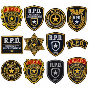Può includere: Una collezione di dodici toppe ricamate con design del R.P.D. Raccoon City Police Department. Le toppe sono principalmente blu navy, oro e bianche, mostrando varie forme di scudi, stelle e cerchi con il testo R.P.D. e 1969.