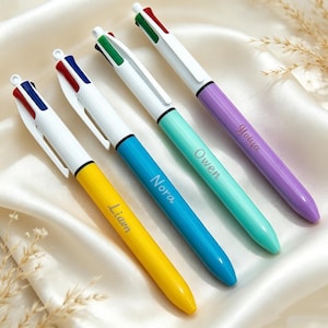 May include: Four multi-color ballpoint pens with white clips and tops featuring red, blue, and green ink selectors. The barrels are yellow, blue, teal, and purple, each engraved with the names Liam, Nora, Owen, and Yoiya respectively.