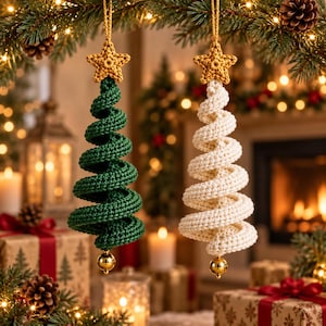 Pode incluir: Dois enfeites de árvore de Natal em forma de espiral feitos de fio de crochê. Uma árvore é verde-escura e a outra é branco-sujo. Cada enfeite apresenta uma pequena estrela dourada texturizada no topo e uma conta dourada brilhante na base.