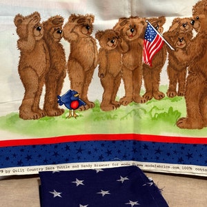 May include: A patriotic fabric panel featuring a line of brown teddy bears saluting the American flag. The fabric is printed with a blue background with white stars and red and white stripes. The text "S by Quilt Country Sara Tuttle and Sandy Brawner for moda www.modafabrics.com 100% cotton" is printed at the bottom of the panel.