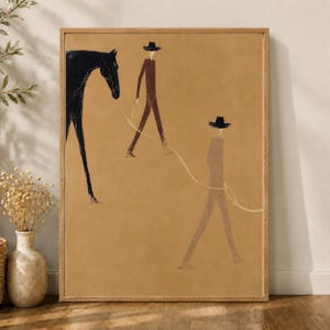 May include: A framed wall art print on a tan background featuring a black horse and two figures wearing wide-brimmed hats. The figures are rendered in brown tones and are connected to the horse by a thin, light-colored line, creating a minimalist scene.
