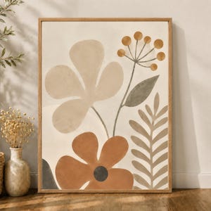 May include: A framed wall art print featuring a botanical illustration with a large beige flower, a rust-colored flower with a dark center, a sprig of small round berries, and a fern-like leaf, all set against a light cream-colored background.