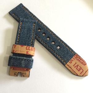 May include: A blue denim watch strap with orange stitching and a brown leather backing. The strap has the text "LEVI'S" and "ORIGINAL" on the back. The strap is 20mm wide.