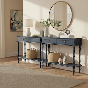 May include: A long, dark navy blue console table featuring four drawers with small gold knobs and a lower shelf. The table is supported by slender, turned legs and holds two woven baskets, decorative vases, a lamp, and books.