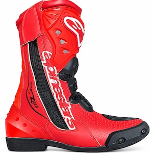 Puede incluir: Una bota de carreras de moto de color rojo brillante con exterior de cuero perforado, paneles protectores negros y un logotipo blanco de Alpinestars en la espinilla. El lateral muestra el texto Supertech en negro, con suela negra y puntera reforzada.