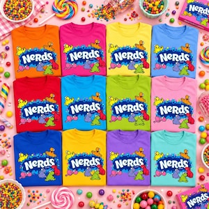 May include: A collection of twelve t-shirts in various solid colors, each featuring the Nerds candy logo with colorful cartoon characters on a blue splat background. The shirts are arranged in a grid surrounded by scattered colorful candies and lollipops.