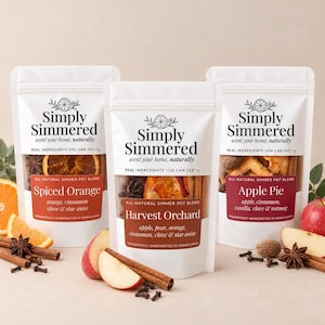 May include: Three white pouches of Simply Simmered potpourri blends labeled Spiced Orange, Harvest Orchard, and Apple Pie. Each pouch features a clear window displaying dried fruit, cinnamon sticks, cloves, and star anise ingredients.