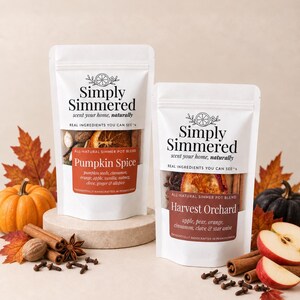 May include: Two white stand-up pouches labeled Simply Simmered. The left pouch is labeled Pumpkin Spice with ingredients including pumpkin seeds, cinnamon, orange, apple, vanilla, nutmeg, clove, ginger, and allspice. The right pouch is labeled Harvest Orchard with apple, pear, orange, cinnamon, clove, and star anise.
