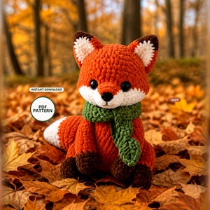 May include: A crocheted fox plush toy with orange fur, a white chest and tail tip, and dark brown paws and ear tips. The fox wears a textured green scarf and has black safety eyes. Text on the image reads: INSTANT DOWNLOAD, PDF PATTERN, EASY.